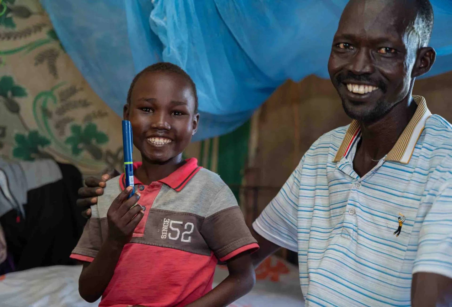 Aher Lual, 11, holds an insulin pen next to his father in their home in Ariath