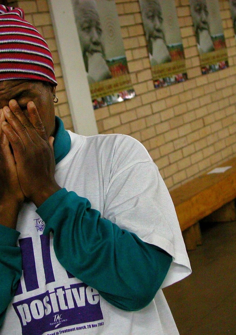 A woman wearing an "HIV Positive" t-shirt closes her eyes for a prayer during Mr Mandela's visit to Siyaphila la HIV Treatment Program hosted by MSF and the Nelson Mandela Foundation. The event was held at the Lusikiki Teacher's Training College.