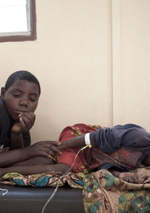 Latifa, 5 years old, falls asleep during the injection of Artesunate to treat the malaria. Her mother stays at her side. Mukenke hospital