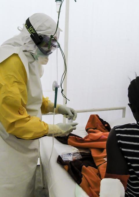 National staff members dressed in PPE attend to a 16 year old girl confirmed with Ebola, in Sierra Leone, 2015