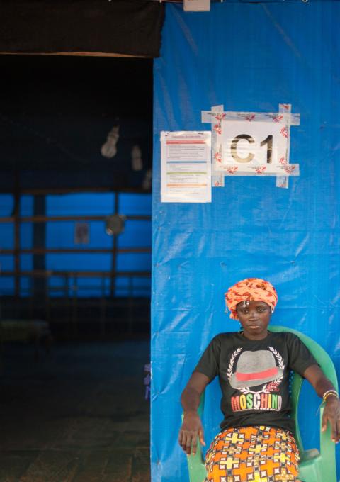 In the MSF Ebola Treatment Center in Guéckédou, Finda (left), and Kadia (right), two Ebola patients participating in the favipiravir trial, relax outside their ward. Inside, MSF staff care for a five year old boy whose mother died from Ebola the previous day.