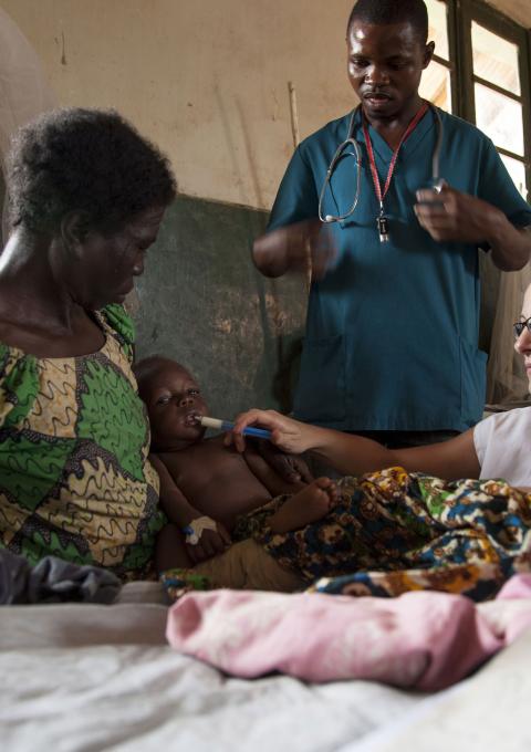 Sophie Allot, a MSF nurse, gives therapeutic milk to a child affected by measles and malnutrition inside the intensive care unit of the Titulé hospital. Malnutrition is a medical complication often associated with measles.