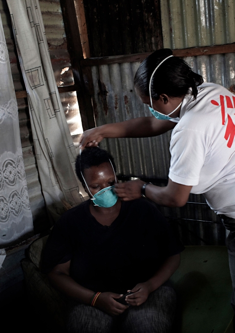 XDR-TB survivor and peer counselor, Xoliswa Hermanus, helps a family member fit a mask to prevent TB infection during a home visit and group counseling session. 