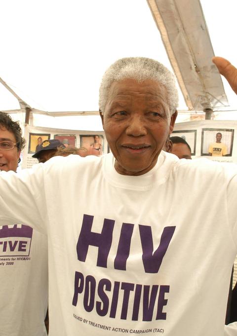 Former South African president Nelson Mandela has accepted the offer of a beneficiary of the project and has changed his shirt for an HIV-Positive T-shirt. See Zackie (Zackie Achmat of the Treatment Action Campaign, a South African NGO {TAC}) just behind.
