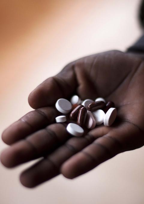 A close-up photo shows pills in the hand of an MDR TB patient taking his Direct Observation Treatment Short Course (DOTs) medication at the Nhlangano TB Ward supported by MSF.