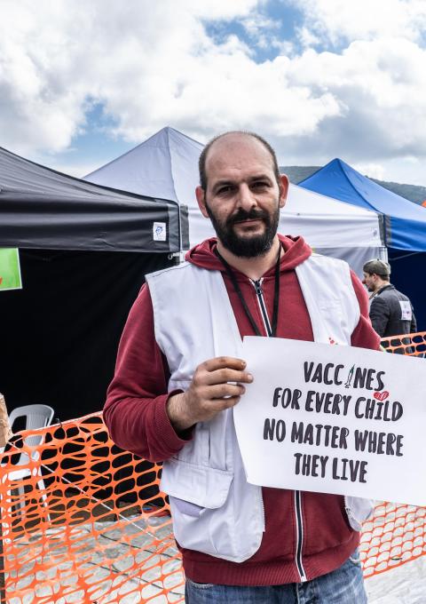 MSF logistician, Athanasios Papadopoulos holding a sign advocating for broader use of the pneumonia vaccine at a lower price