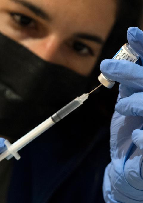 A staff from checks the vaccine before administering it. 