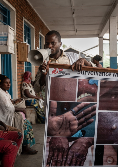 An MSF health promoter explains the signs and symptoms of mpox to camp people present inside the health centre supported by MSF in the Kanyaruchinya displacement site, on the outskirts of Goma.