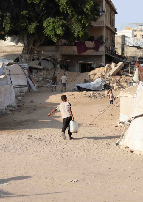 A little boy struggles under the weight of a water jerrycan to bring it back to his displaced family's tent. This daily burden, carried by children, is a direct result of the man-made water crisis. With 70% of Gaza's piped water lost to bomb-damaged networks, water trucking is the only source of water for thousands in Gaza, however, water trucking is frequently hindered by militarized zones and constant bombardment.