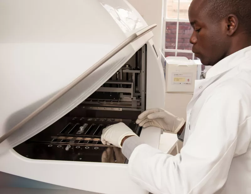 An HIV lab worker at the Namitambo Health Centre works with diagnosis machine capable of testing 140 patients providing results on the same day, Malawi 2013.