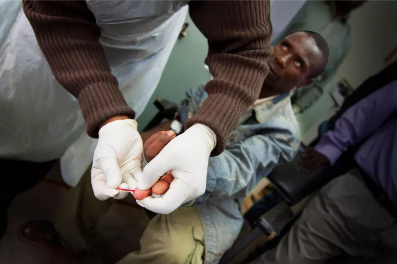 A community health worker at Bvumbe Health Centre pricks a man’s finger for a sample used in a dried blood spot (DBS) viral load test