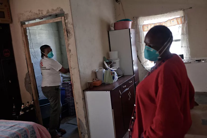 XDR-TB survivor and peer counselor, Xoliswa Hermanus, inspects the family home of Jonas Cikizwa (right); a woman infected with extremely drug-resistant tuberculosis (XDR-TB), HIV and diabetes. Khayelitsha township, near Cape Town, South Africa.