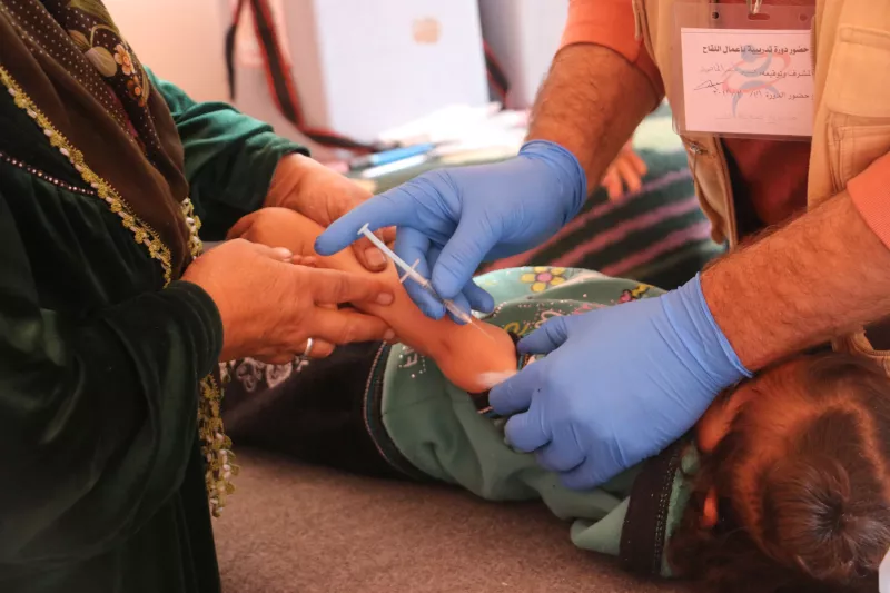 A mother holds her son´s hand while a nurse is vaccinates him as part of a MSF vaccination campaign in west Aleppo countryside targeting children from two months to five years old in Kafer Karmeen Health center.