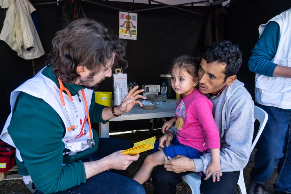 MSF medical doctor, Stefanos Tsallas vaccinates a child from refugee camp against pneumonia