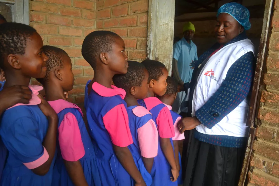 Tifera, a Médecins Sans Frontières interpreter, assists the girls to get in line as they arrive for their vaccinations at Lisawo Primary School. 
