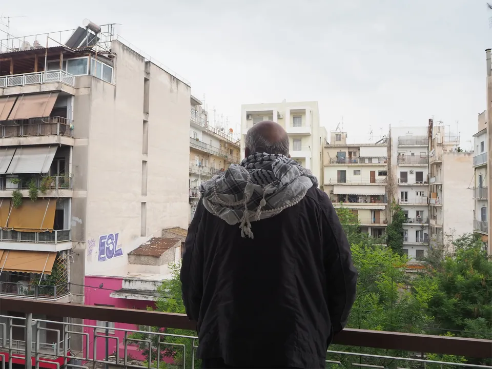 Ghassan stands on his balcony. Athens, Greece.