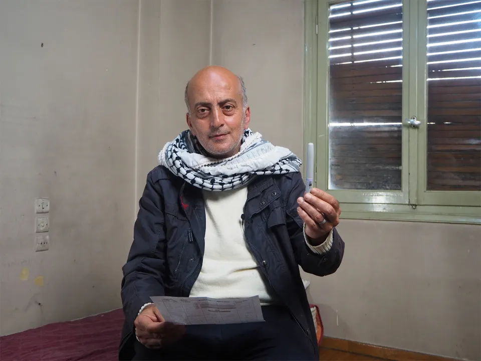Ghassan holds up his insulin in a pen. Athens, Greece.