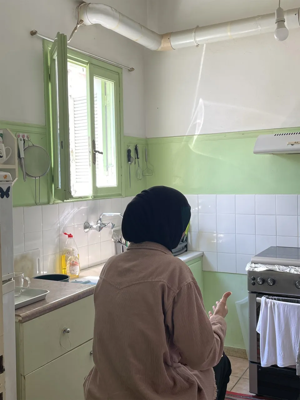 Amina sitting in her kitchen and sharing her story. Athens, Greece.