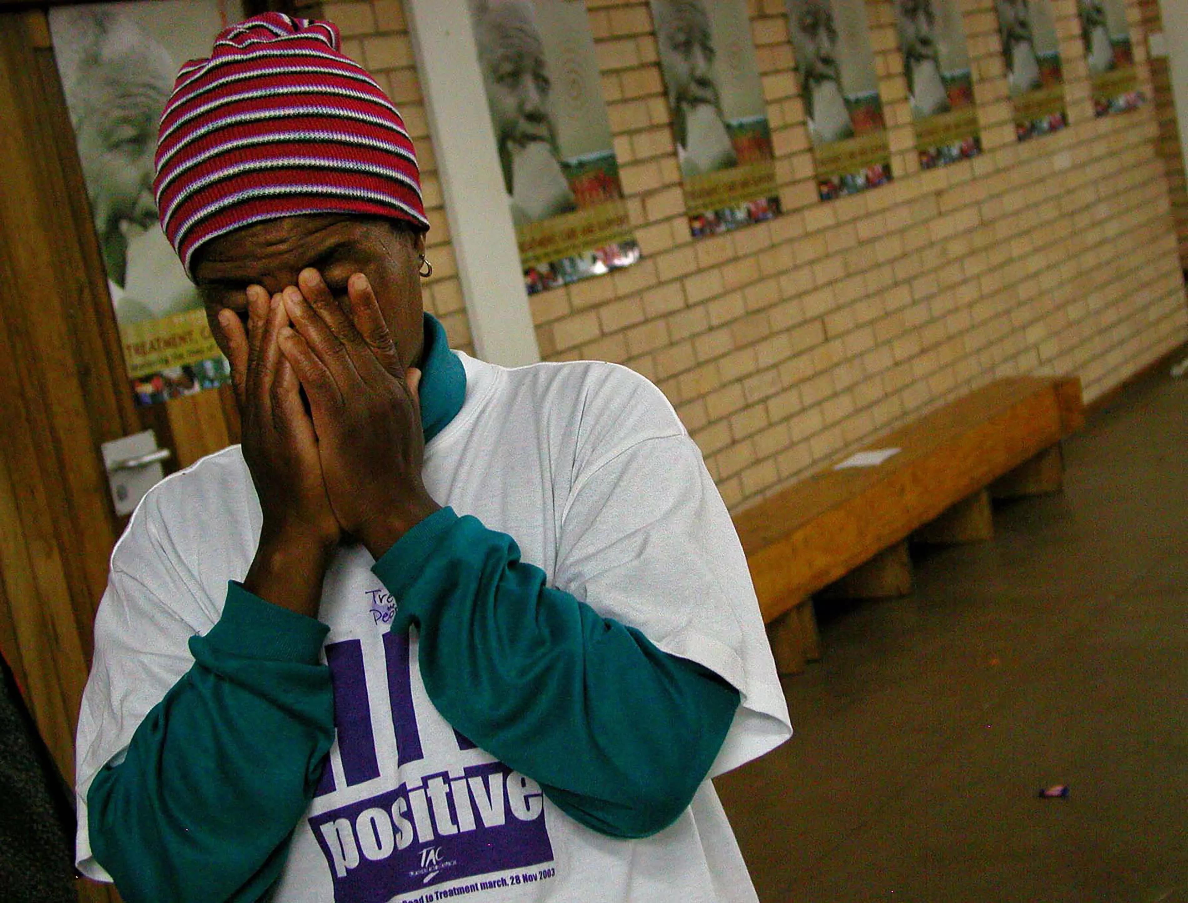 A woman wearing an "HIV Positive" t-shirt closes her eyes for a prayer during Mr Mandela's visit to Siyaphila la HIV Treatment Program hosted by MSF and the Nelson Mandela Foundation. The event was held at the Lusikiki Teacher's Training College.