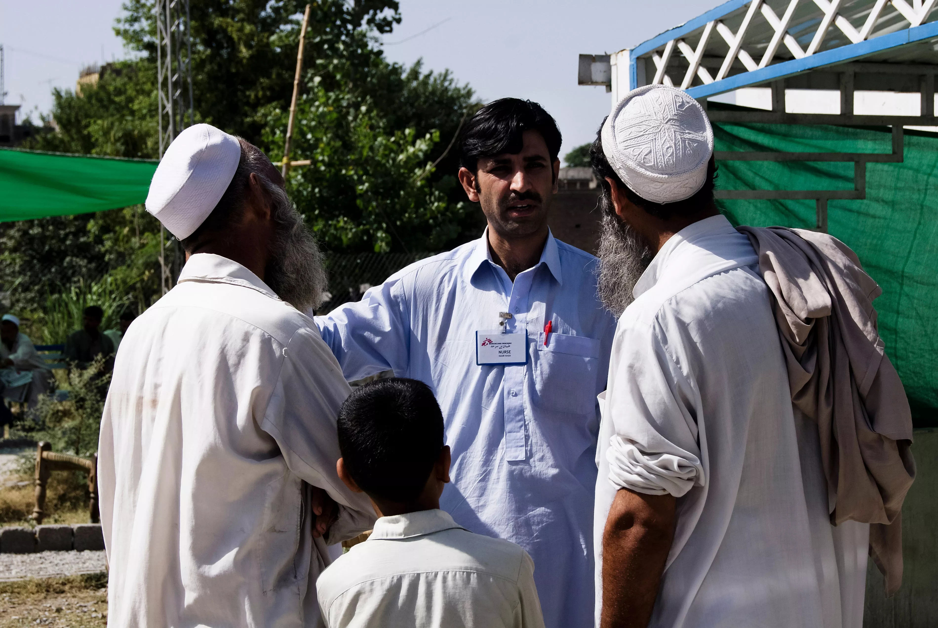 Nurse Nasir answering questions after a health promotion about Hepatitis B and C in the male waiting area. Dargai, Pakistan.