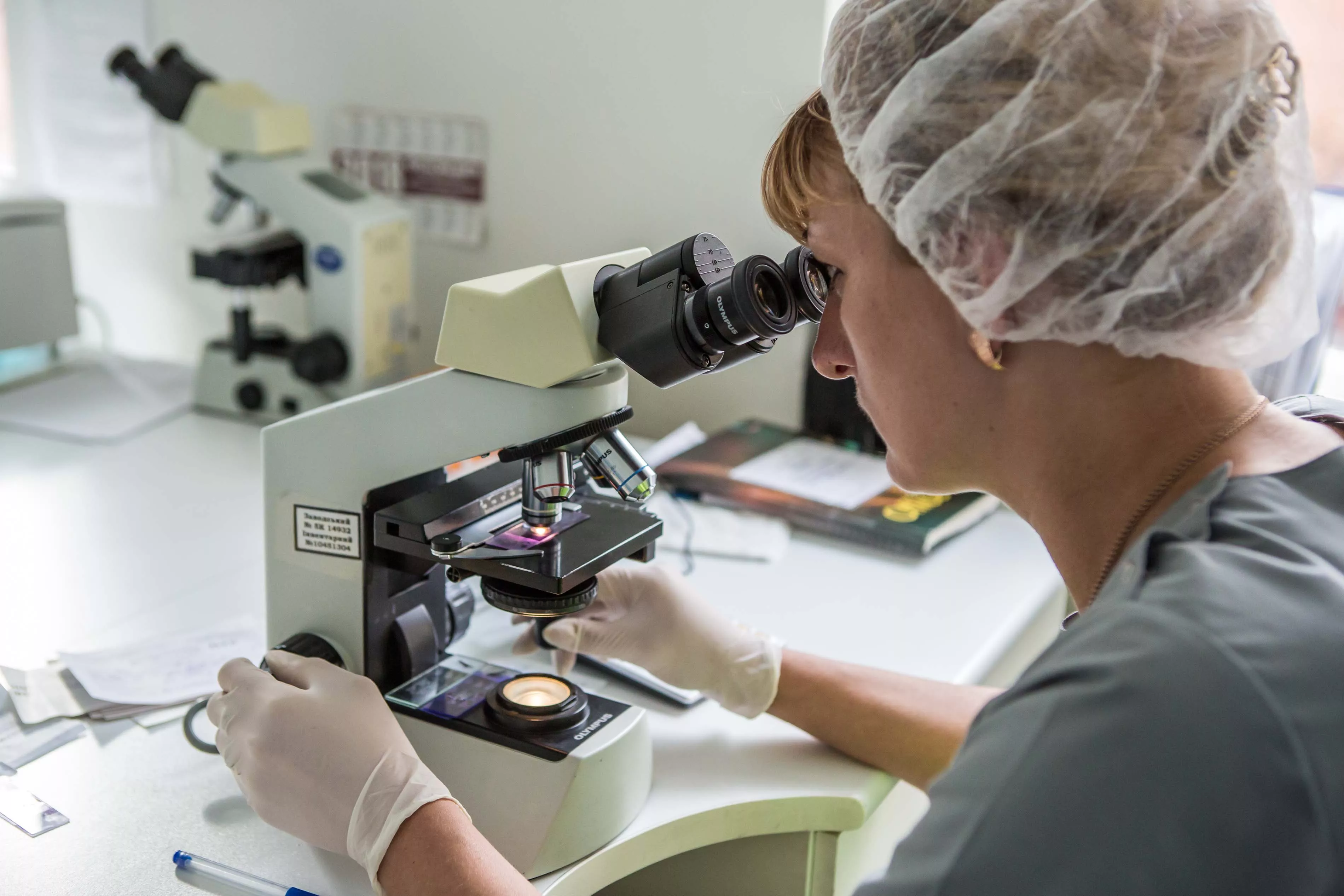 Biologist looking at a slide through a microscope to get a white blood cell count, in the laboratory of the Zhytomyr Regional TB Dispensary. 