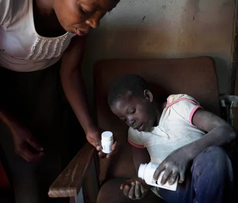 Ten year old Tanya, who is HIV positive and unable to walk, takes her medication with the help of her neighbor Florence who she calls ‘Mama’. Her mother died in 2010. Florence, Tanya and her mother we all part of the first group of patients to join MSF and the Ministry of Health and Childcare’s Epworth HIV program a decade ago, 28 October 2016. 