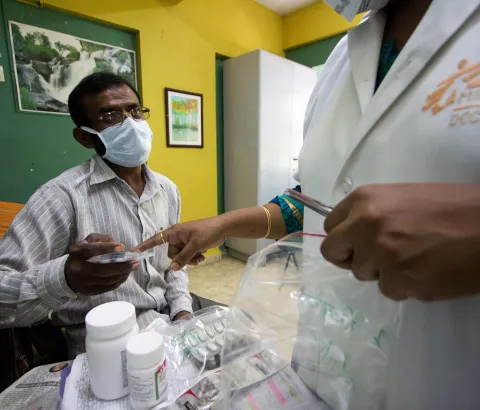 MSF Nurse handing over 3rd line ARTs to a patient living with HIV.