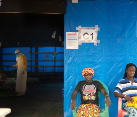 In the MSF Ebola Treatment Center in Guéckédou, Finda (left), and Kadia (right), two Ebola patients participating in the favipiravir trial, relax outside their ward. Inside, MSF staff care for a five year old boy whose mother died from Ebola the previous day.