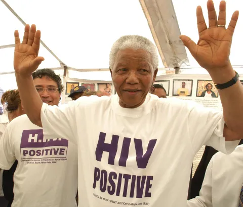Former South African president Nelson Mandela has accepted the offer of a beneficiary of the project and has changed his shirt for an HIV-Positive T-shirt. See Zackie (Zackie Achmat of the Treatment Action Campaign, a South African NGO {TAC}) just behind.