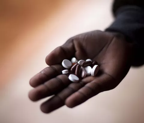 A close-up photo shows pills in the hand of an MDR TB patient taking his Direct Observation Treatment Short Course (DOTs) medication at the Nhlangano TB Ward supported by MSF.