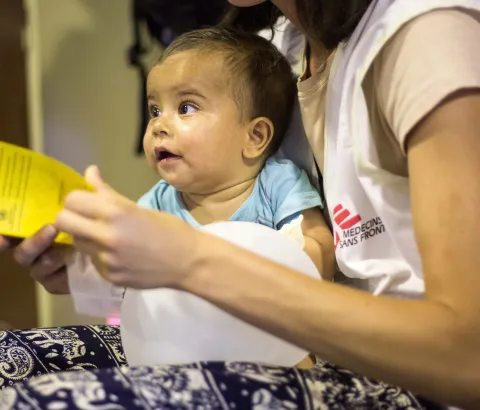 MSF staff taking care of a child after he has been vaccinated. Photograph by Pierre-Yves Bernard