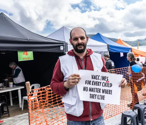 MSF logistician, Athanasios Papadopoulos holding a sign advocating for broader use of the pneumonia vaccine at a lower price