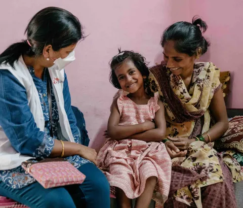 Vaishnavi, a 7-year-old DRTB (Drug Resistant​ Tuberculosis) patient interacts with Prachi, an MSF nurse as her mother Vishaka holds her.​
