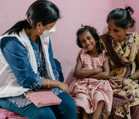 Vaishnavi, a 7-year-old DRTB (Drug Resistant​ Tuberculosis) patient interacts with Prachi, an MSF nurse as her mother Vishaka holds her.