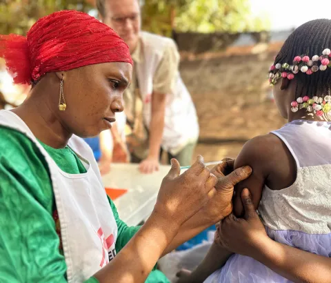 Diaka Kaba, a member of the MSF team, administers a diphtheria vaccine to a child in the Hèrèmakonön neighbourhood of Siguiri, Guinea as part of a vaccination campaign. 2026. © Mohamed Mara, MSF.